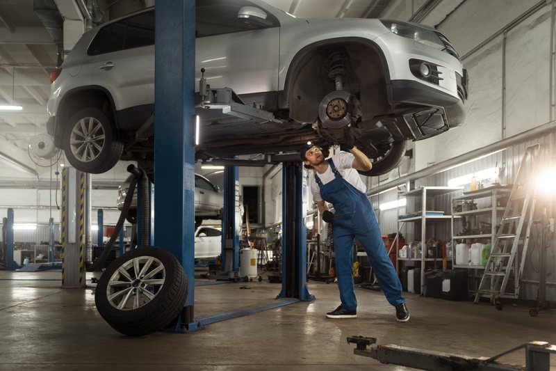Mechanic working on car suspension system at Torque Experts repair shop, Madhapur