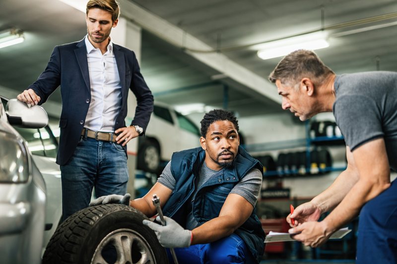 Two mechanics cooperating on tyre repair at Torque Experts auto repair shop