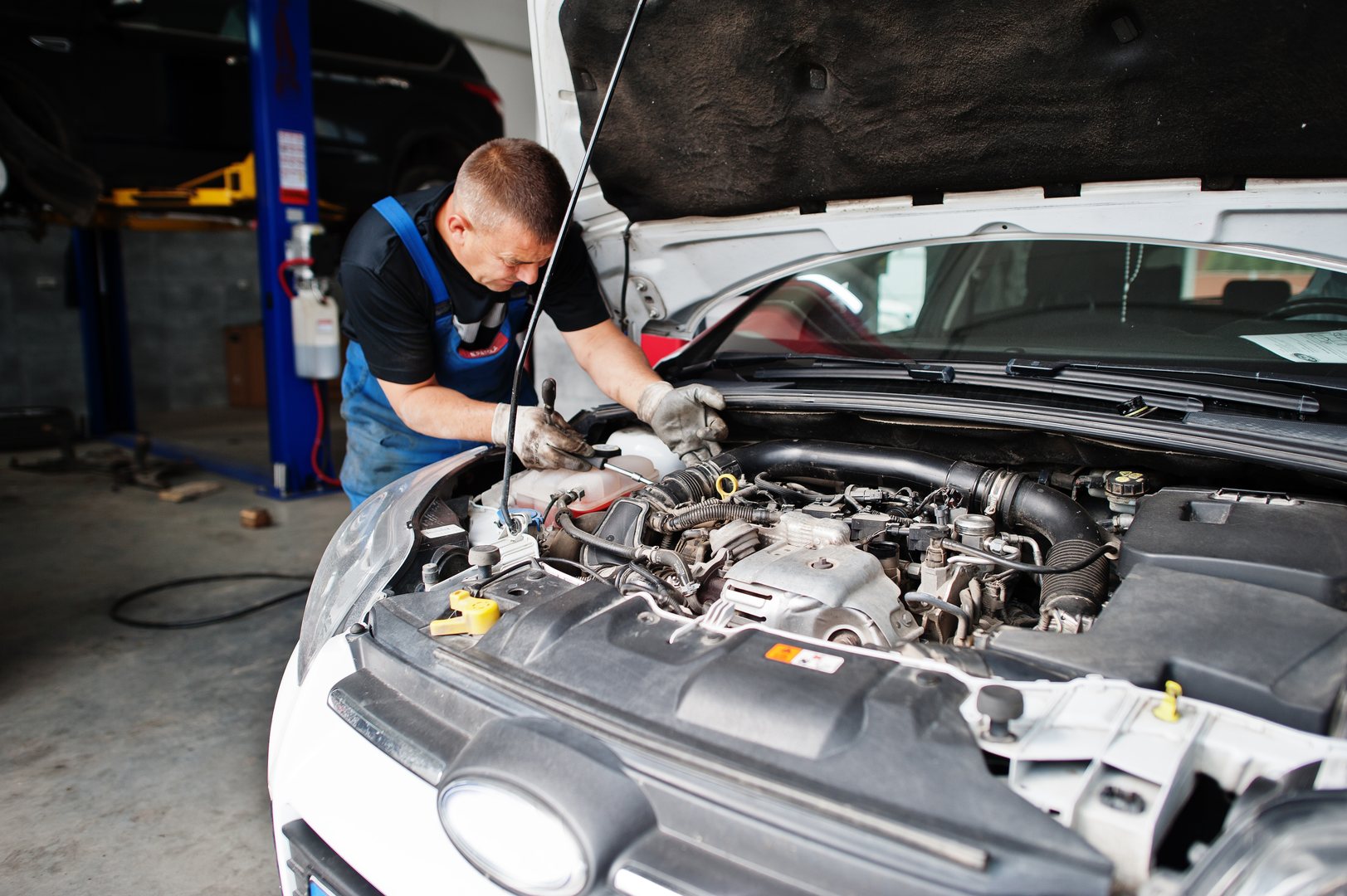 Mechanic in uniform inspecting car engine at Torque Experts auto service, Madhapur